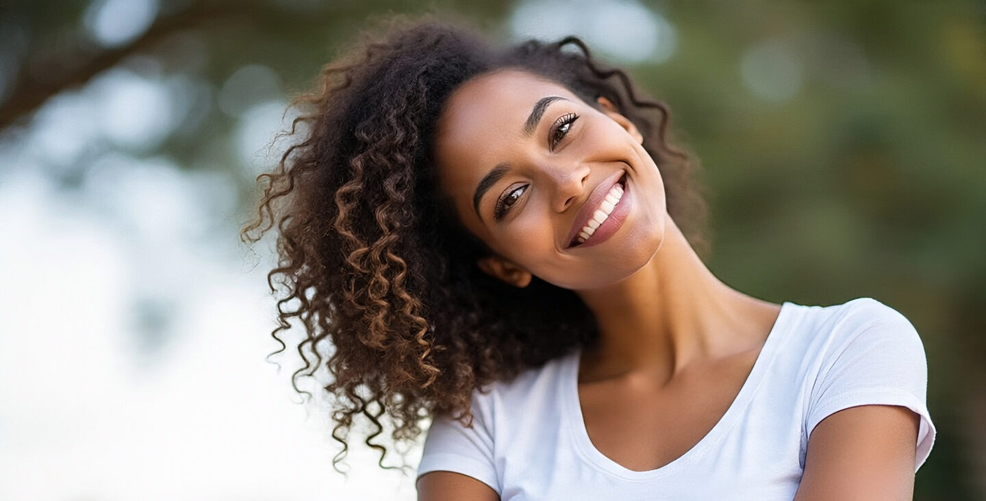 Confident young woman smiling outdoors with fresh and healthy look, representing good intimate hygiene and women’s wellness.